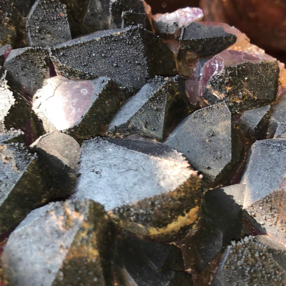 Macro close-up of natural black hematite crystallization overgrowing amethyst quartz points, rare geological mineral specimen texture.