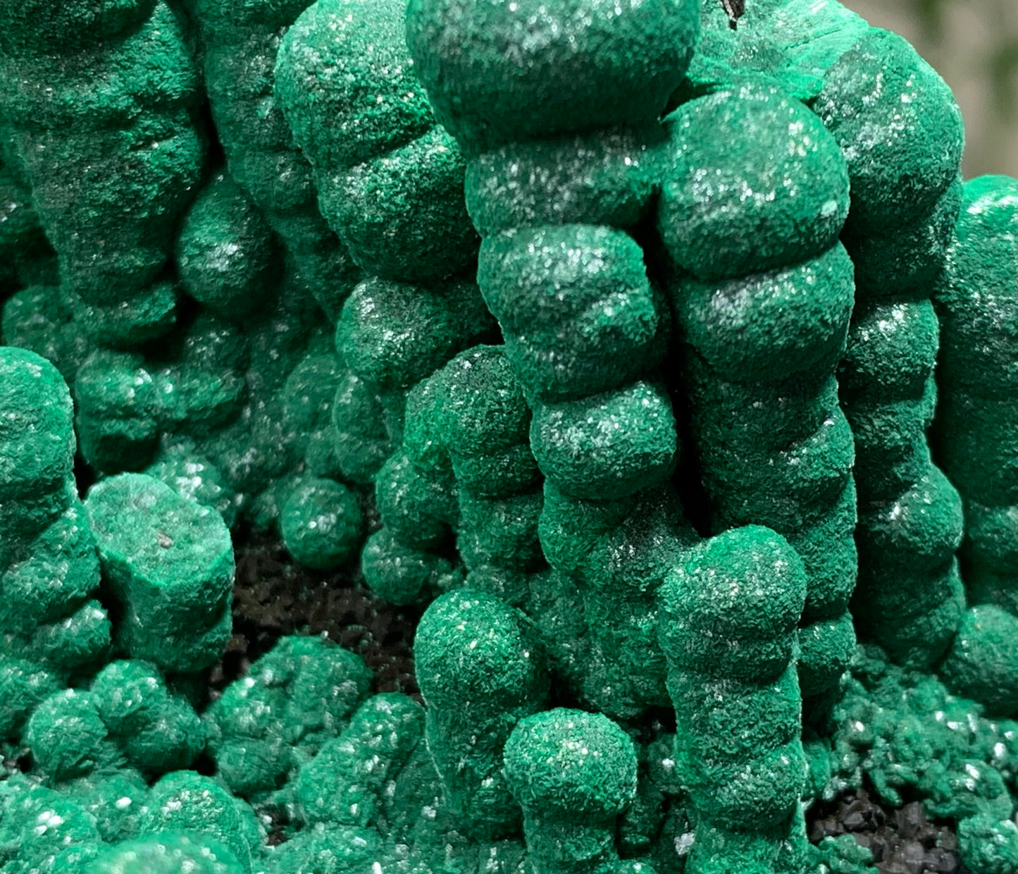 Macro photography of natural stalactitic malachite showing unpolished crystal formations and dense microcrystalline velvet texture.