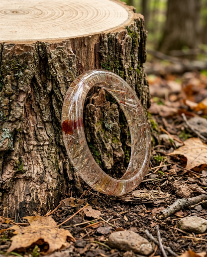 Natural Super Seven crystal bangle resting on a rugged tree stump with fallen autumn leaves, mindfulness nature jewelry and forest earth aesthetic by STILLMANTLE
