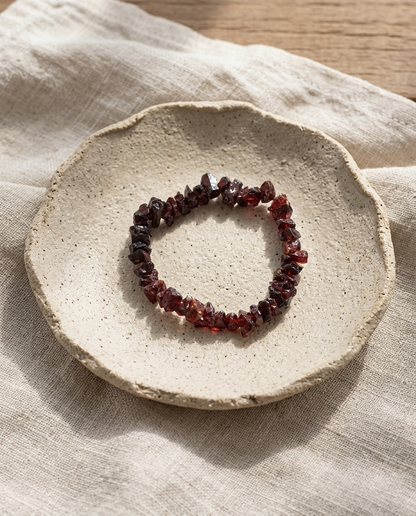 Top view of raw dark red garnet stone bracelet in a minimalist textured bowl, zero-metal healing earth jewelry by STILLMANTLE