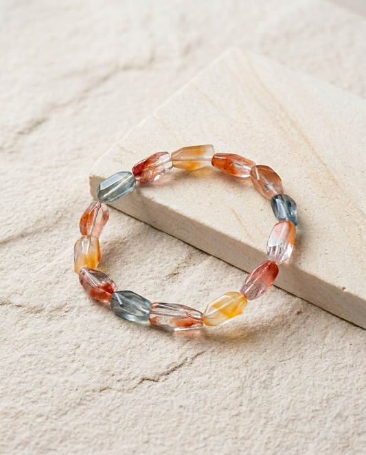 Faceted multicolor amphibole quartz bracelet resting on minimalist textured sandstone, ethereal angel hair crystal and quiet luxury earth element jewelry by STILLMANTLE