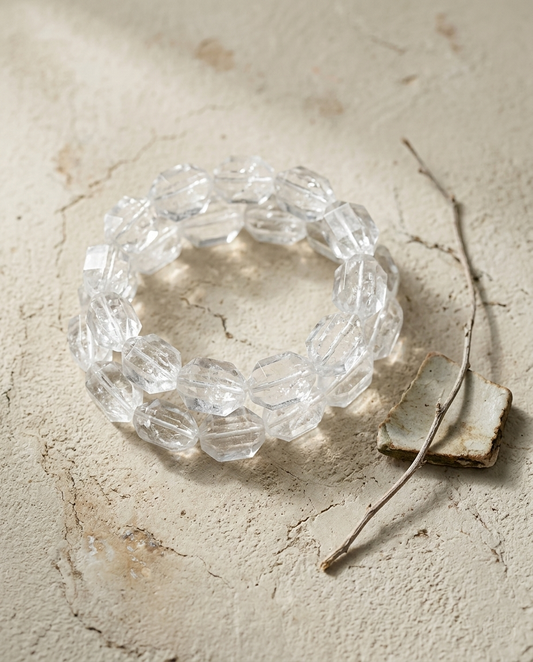 ⁠Close-up of asymmetric faceted clear quartz crystal bracelet on textured light stone, brutalist quiet luxury earth element jewelry by STILLMANTLE⁠