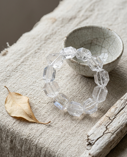 Custom faceted clear glacial quartz bracelet on weathered driftwood beside a wabi-sabi ceramic cup, water-clear minimalist organic jewelry by STILLMANTLE⁠