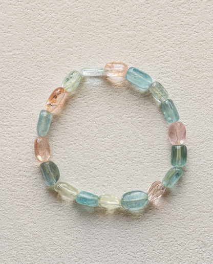 Macro close-up of a natural mixed beryl bracelet showing high transparency blue, pink, and yellow column crystals, unheated luxury mineral jewelry.
