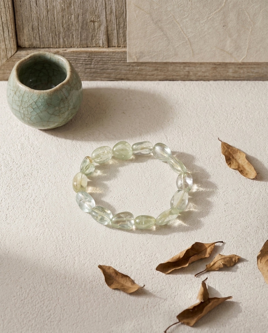 High clarity pale green beryl bracelet with aquamarine and heliodor, styled with dry autumn leaves, crackle glaze celadon cup and weathered wood, organic wabi-sabi jewelry aesthetic.⁠