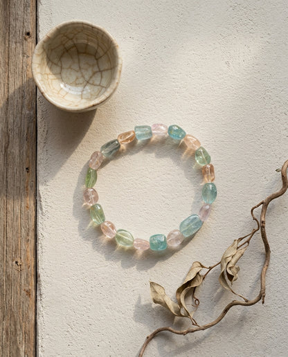 ⁠Natural pastel mixed beryl bracelet with morganite and aquamarine, styled in dramatic sunlight with crackled ceramic cup and dry branch, organic modern wabi-sabi jewelry aesthetic.⁠