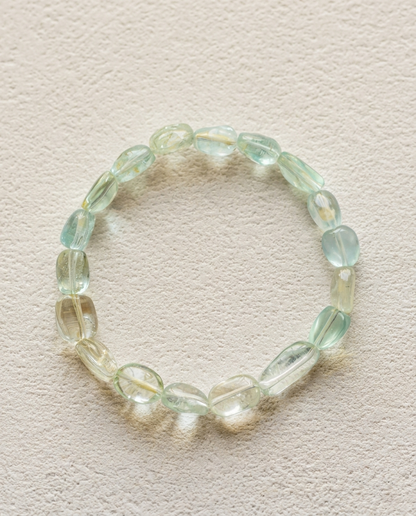 Close up of high clarity undyed beryl gemstone bracelet, showing asymmetrical raw tumbled aquamarine and green beryl crystals with natural internal inclusions, luxury minimalist mineral jewelry.