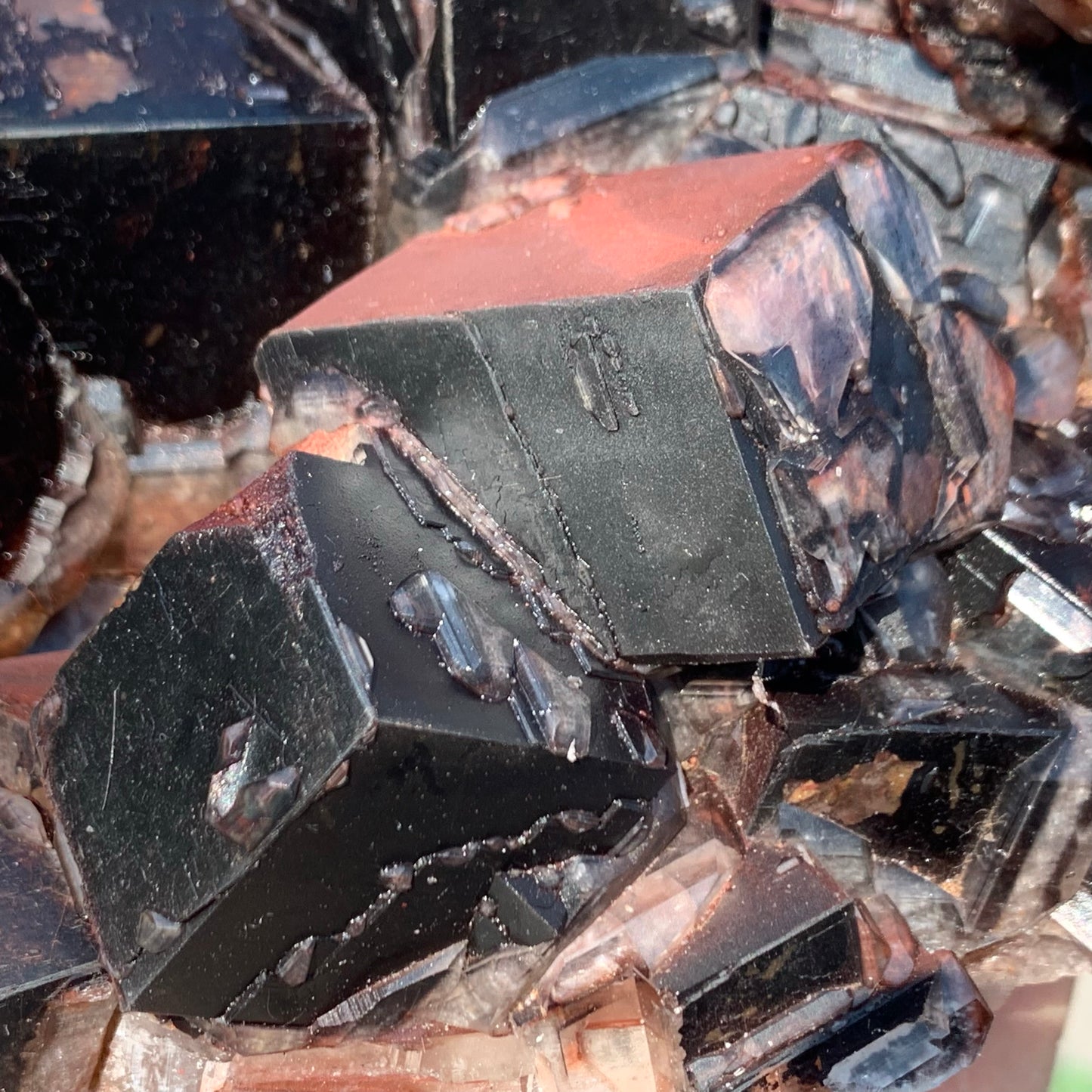 Macro photography of natural calcite rhombohedrons, highlighting the sharp geometric crystal formations and deep crimson hematite inclusions.⁠