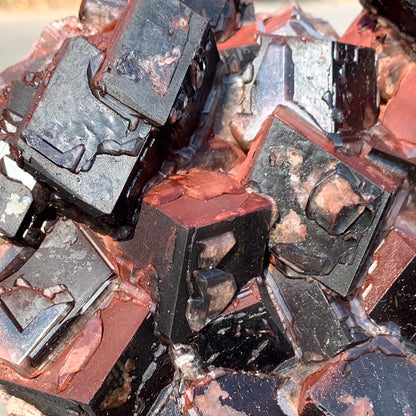 Close-up texture of a raw hematite calcite specimen, revealing the sparkling microcrystalline quartz overgrowth on the dark geometric faces.⁠