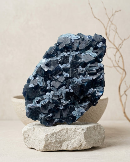 Raw bi-face blue fluorite mineral specimen styled with ceramic bowl and branches, organic modern gallery art.⁠