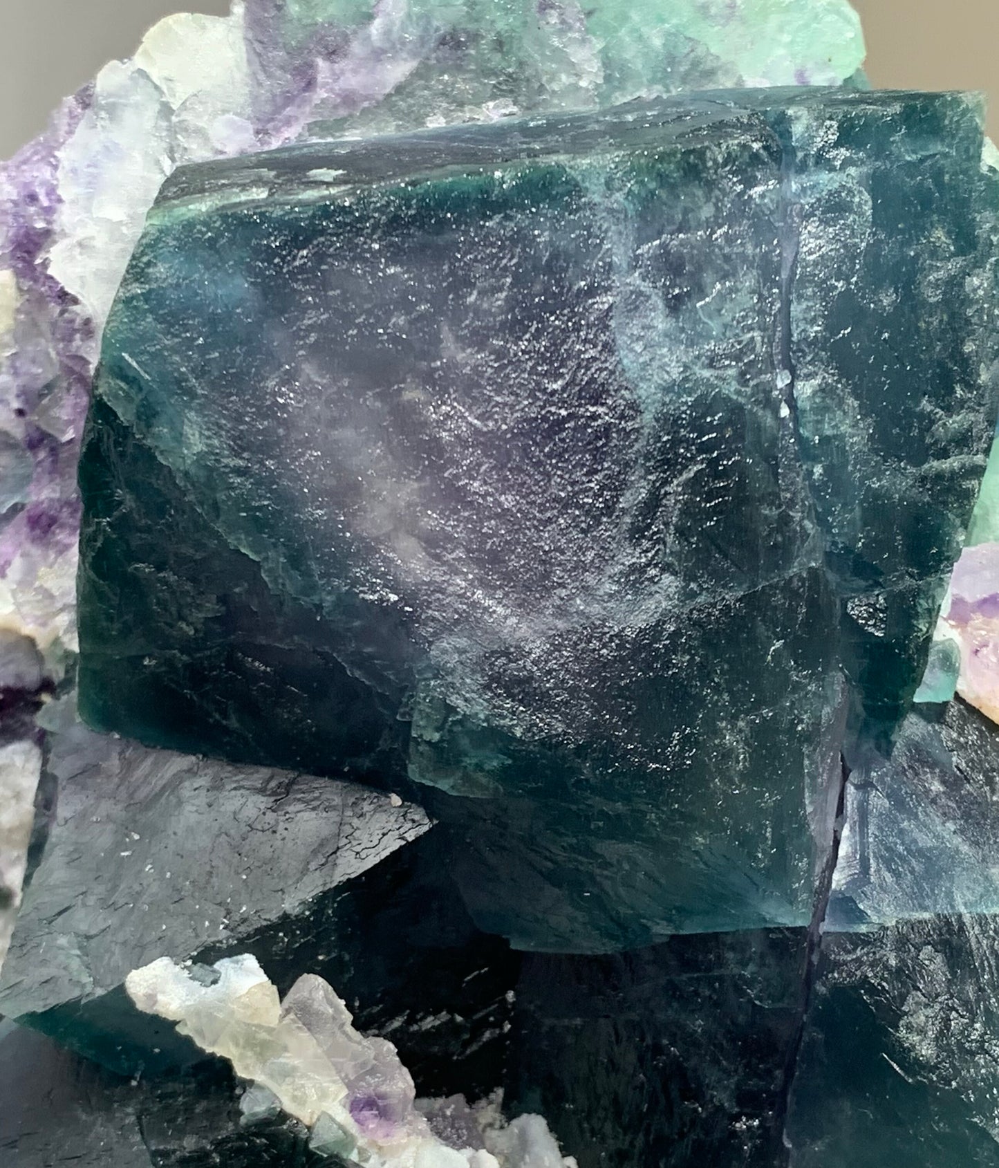  Macro photograph showcasing the sharp cubic geometry and deep teal-purple color zoning of a natural fluorite crystal cluster.