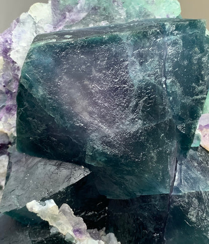  Macro photograph showcasing the sharp cubic geometry and deep teal-purple color zoning of a natural fluorite crystal cluster.
